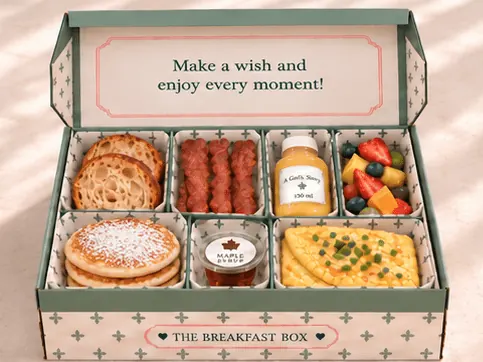 A close-up birthday breakfast box opening to reveal pancakes, savoury breakfast, fruit and a birthday message